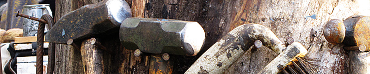 blacksmith tools hangin on a tree stump.