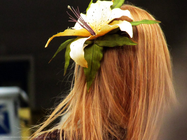 back of a ladies head. she has red hait and a flower in her hair.