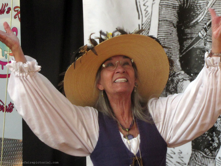 LISA in Straw hat, bodice and blouse. her arms waving over her head.