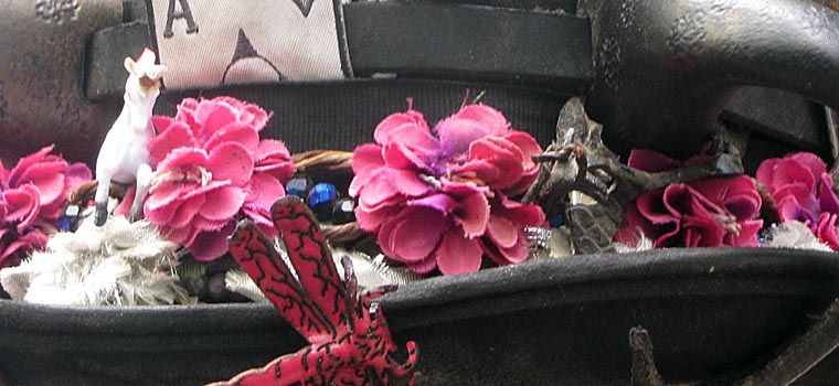the brim of a hat with pink roses, dragonfly, and a toy llama. 