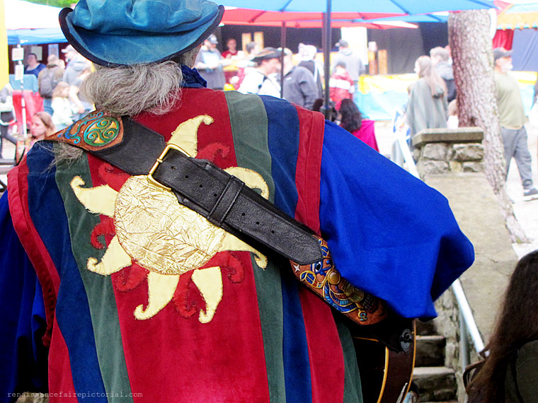 A man's back. He robe is reb.blue, and green with the Sun in the center.