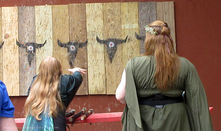 Young girl throwing an axe at the at the axe throw wall.