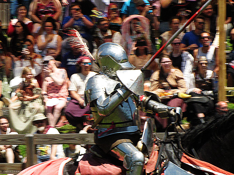 Woman kneeling with her head thrown back. she's holding two sticks one with a flame on it one without. her tounge has a flame on it. she just tranfered the flmae fromstick to her tounge.