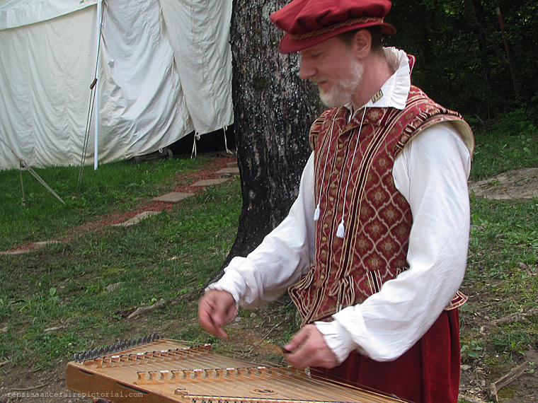 man standing playing a hammer dulcimer
