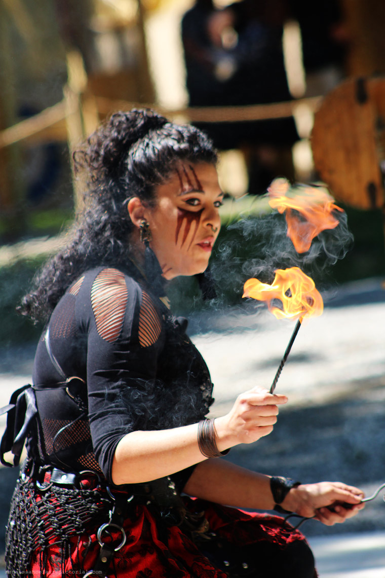 dark haired woman. she kneeling and has just lit a toruch. she's watching the flames.