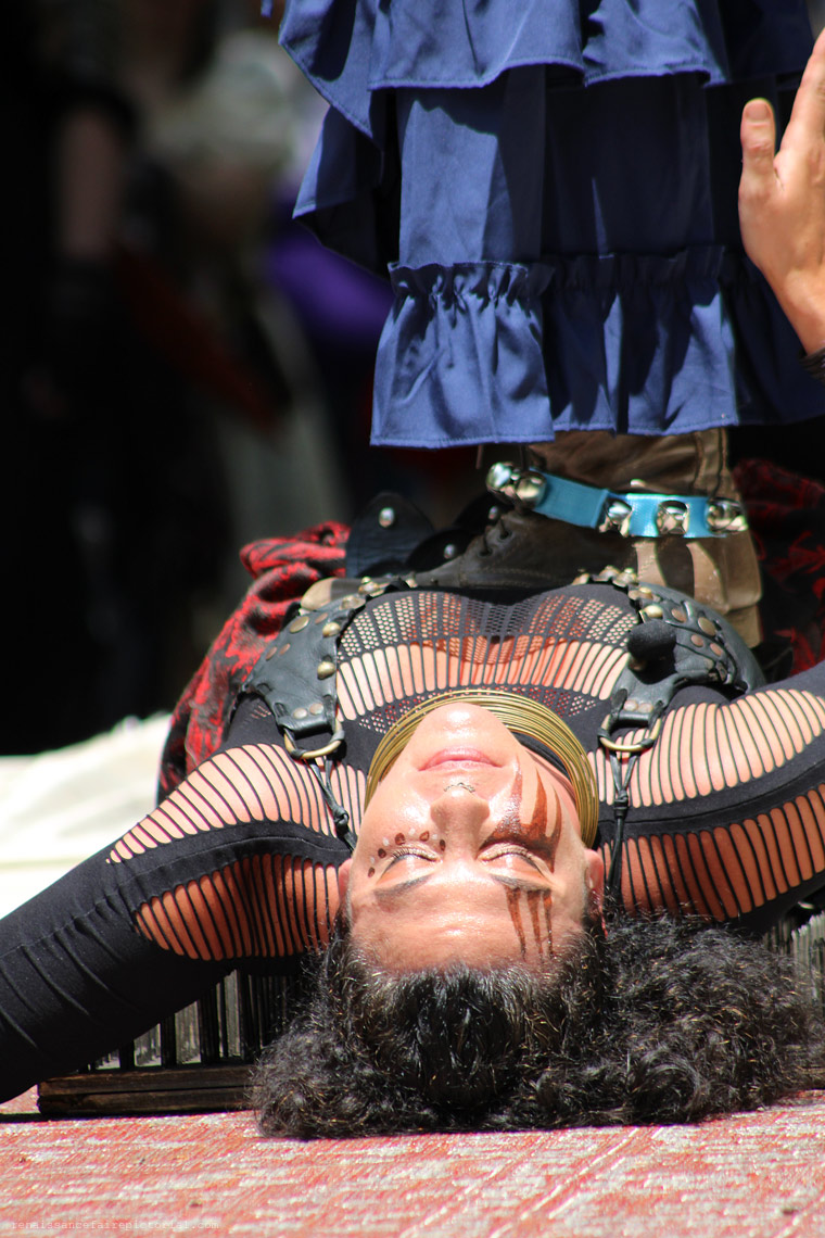 woman on bed of nails. you can see boots from someone standing on her.