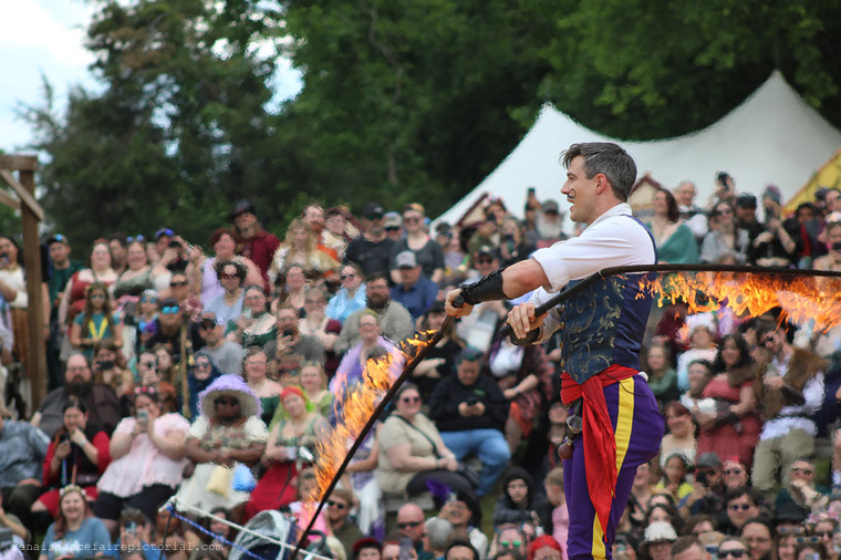 man swinging whip that are on fire.