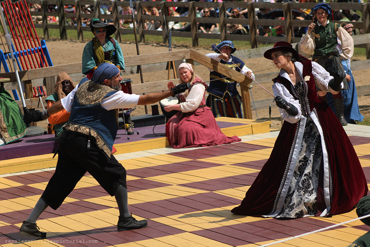 two men on stage . one has his arm behind the other. he showing the other man money that he pull of the other's wallet.