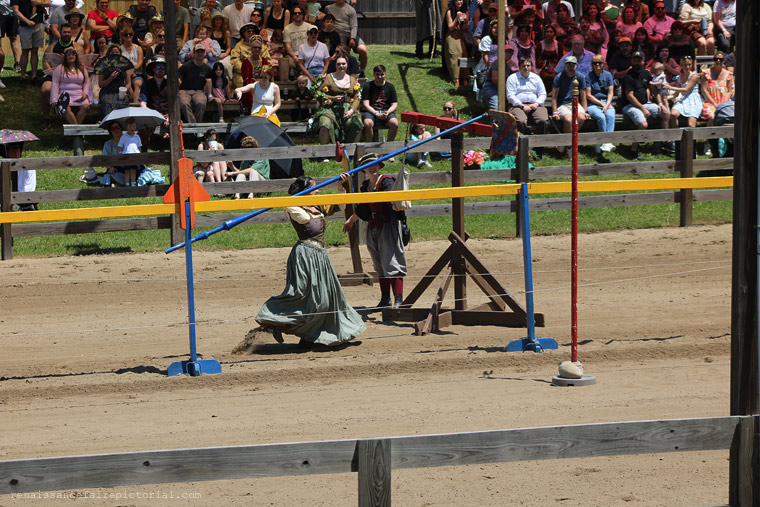 woman running with long pole.she lifting it up to hit a target.