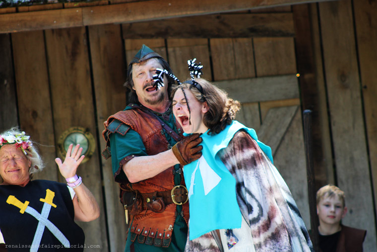 Robin hood show. Girl playing Marian is screamin. while woman playing sheriff is grimacing at marian scream.